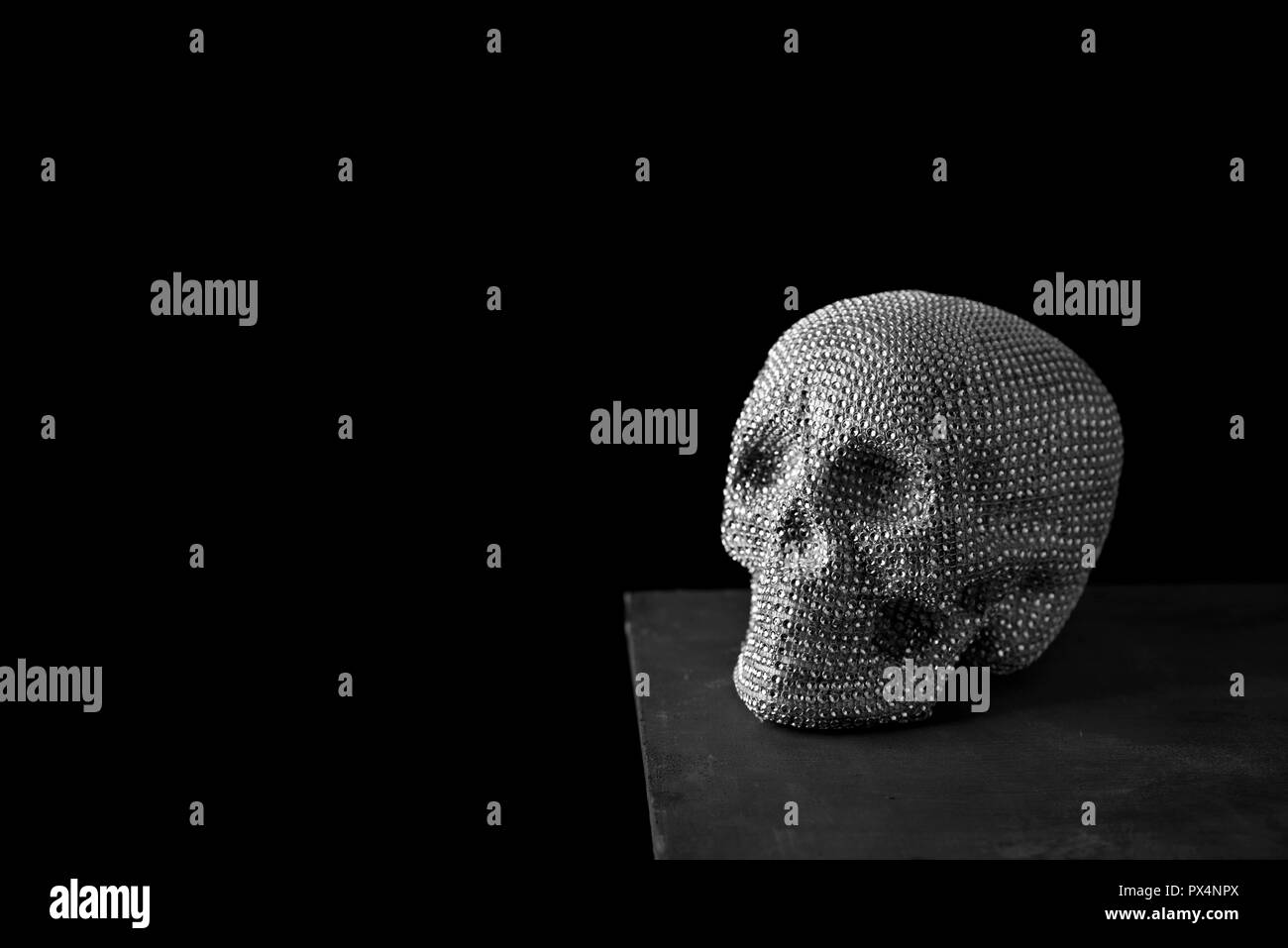 Libre d'un crâne brillant sur une surface gris foncé, sur un fond noir, avec un peu d'espace blanc sur la gauche Banque D'Images
