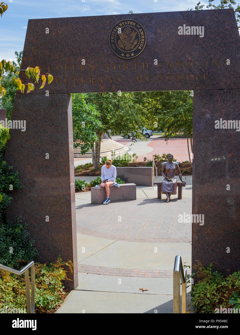 ASHEVILLE, NC, USA-10/17/18 : Le Veterans Memorial dans Pack Square, Asheville, NC, USA, avec une jeune femme assise à côté de la sculpture. Banque D'Images