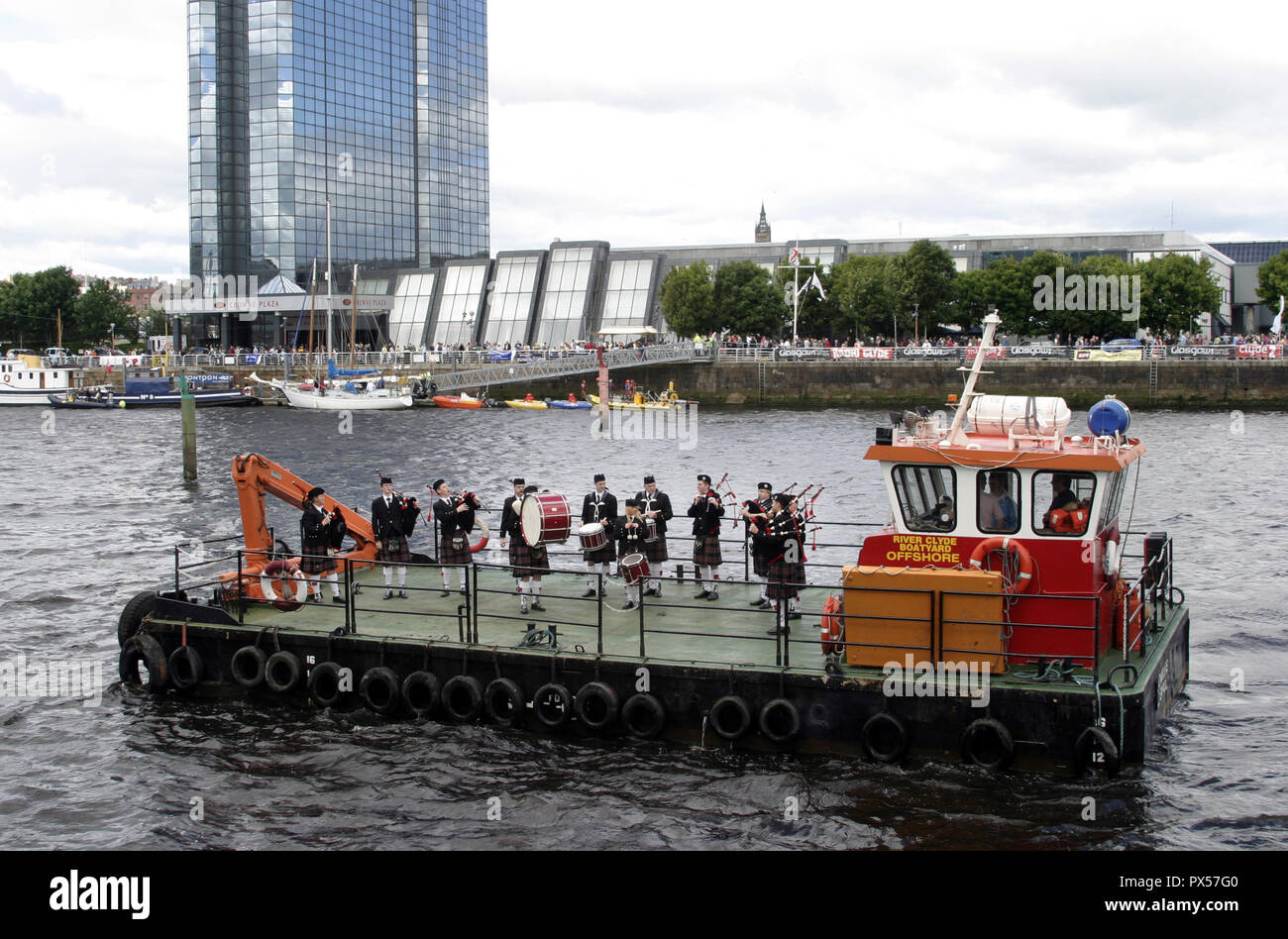 Dans le cadre de la rivière Glasgow Festival, un pipe band traditionnel prend à l'eau pour amuser les spectateurs sur les rives à Glasgow, Ecosse Banque D'Images