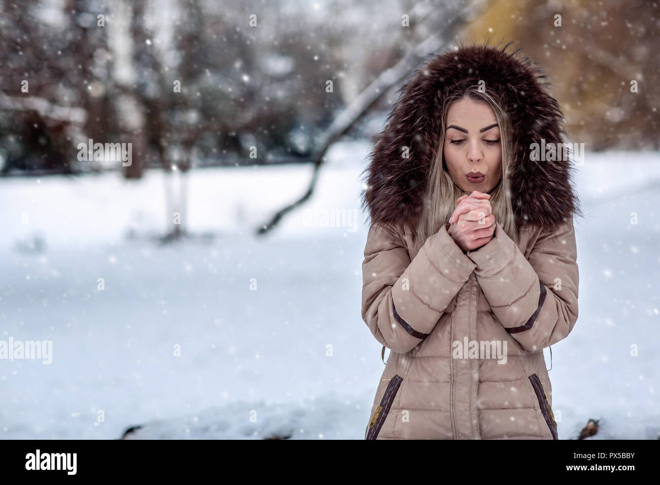 Jeune femme en hiver neige jour souffler sur ses mains froides Banque D'Images