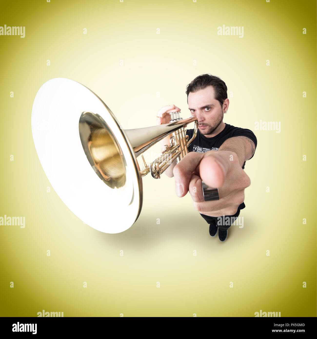 Drôle homme joue trompette pointant doigt sur appareil photo. Studio photo créatif Banque D'Images