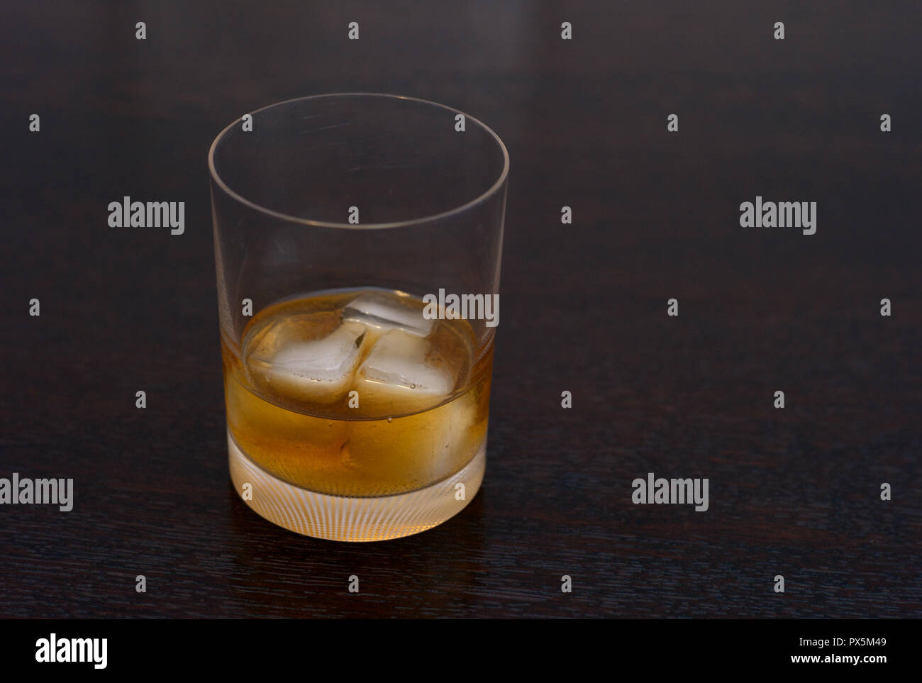 Le Scotch whisky, Bourbon, ou de rhum sur les rochers dans un élégant Tumbler sur une table en bois foncé Banque D'Images