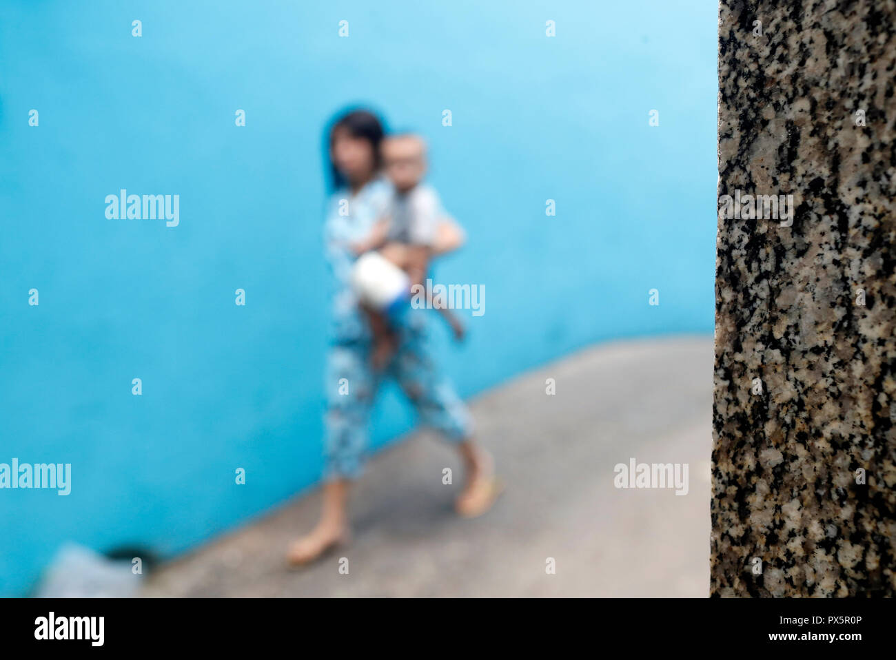 Fille qui marche sur une petite rue contre un mur bleu. Homme marchant sur une petite rue contre un mur bleu. Ho Chi Minh Ville. Le Vietnam. Banque D'Images