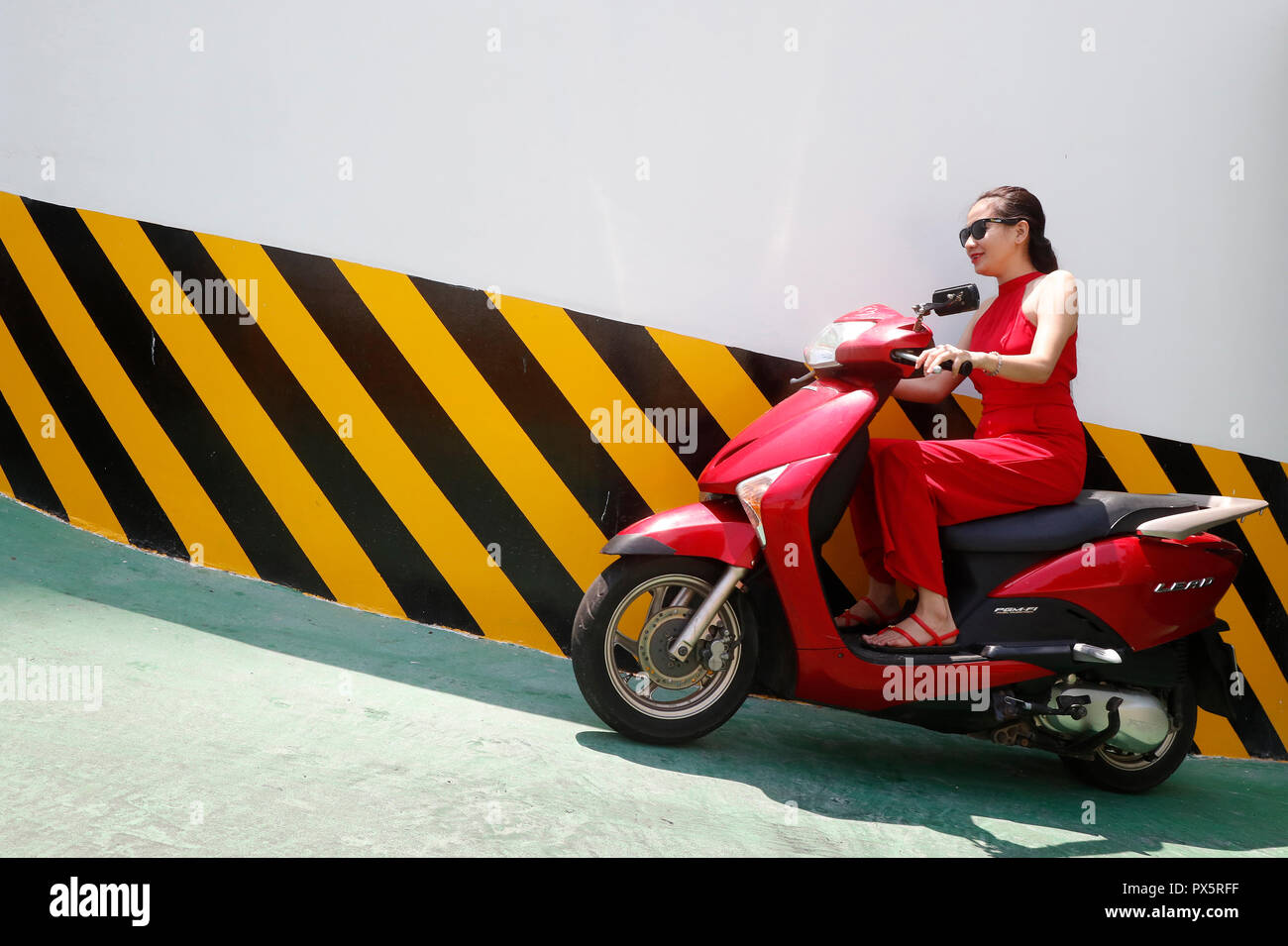 Femme au volant d'un scooter à partir d'un parking gratuit. Notre annuaire d'entreprises. Le Vietnam. Banque D'Images