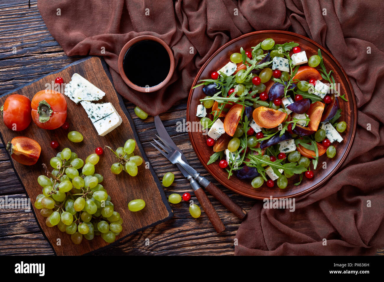 Salade d'automne délicieux avec du chocolat, kaki, moule fromage bleu raisin vert, tranches de prune et la roquette sur une plaque de faïence avec des ingrédients sur une Banque D'Images