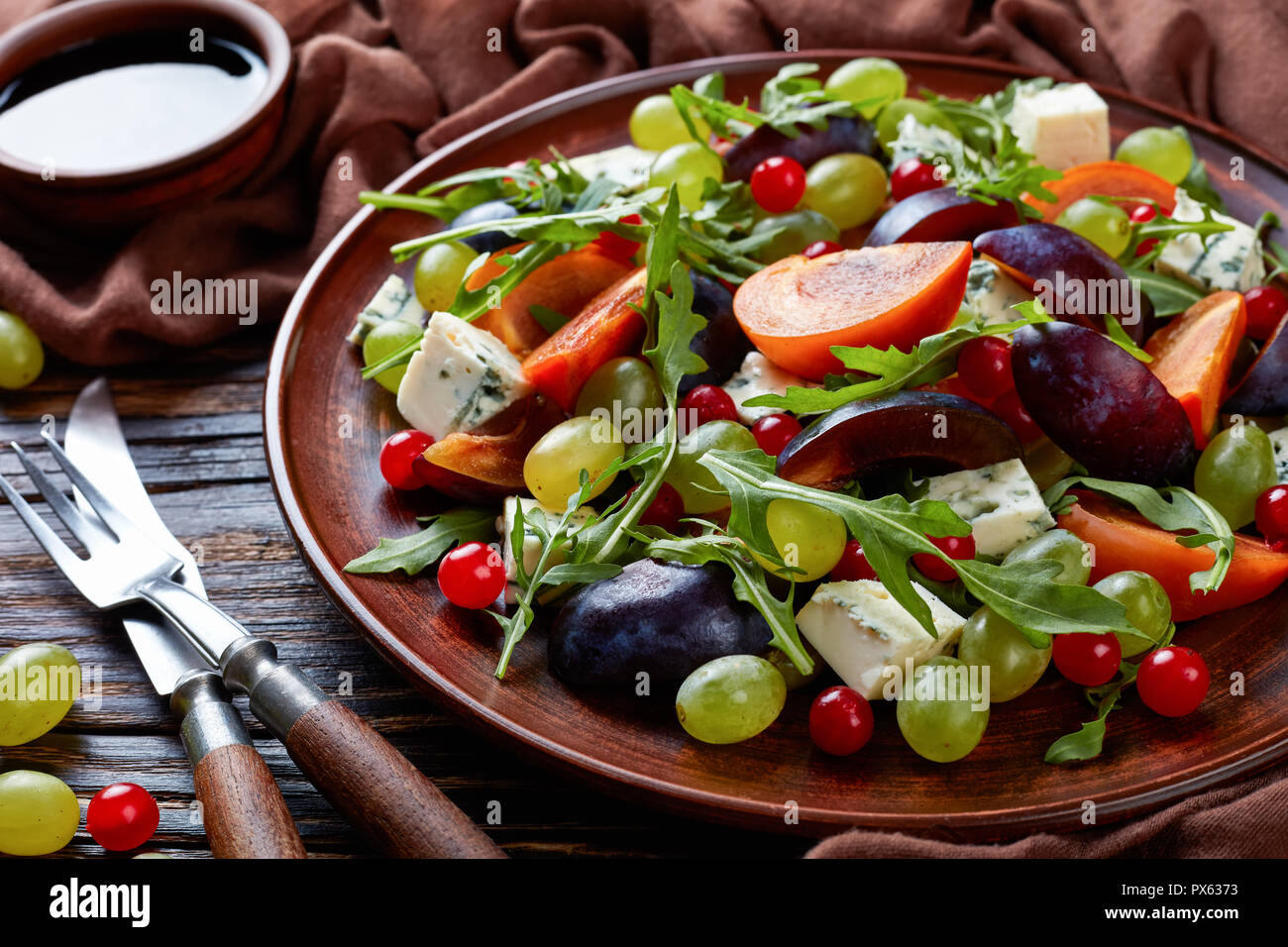 Close-up of delicious salade d'automne au chocolat avec moule bleu kaki, fromage, raisin vert, tranches de prune et la roquette sur une plaque de faïence avec ingrédients Banque D'Images