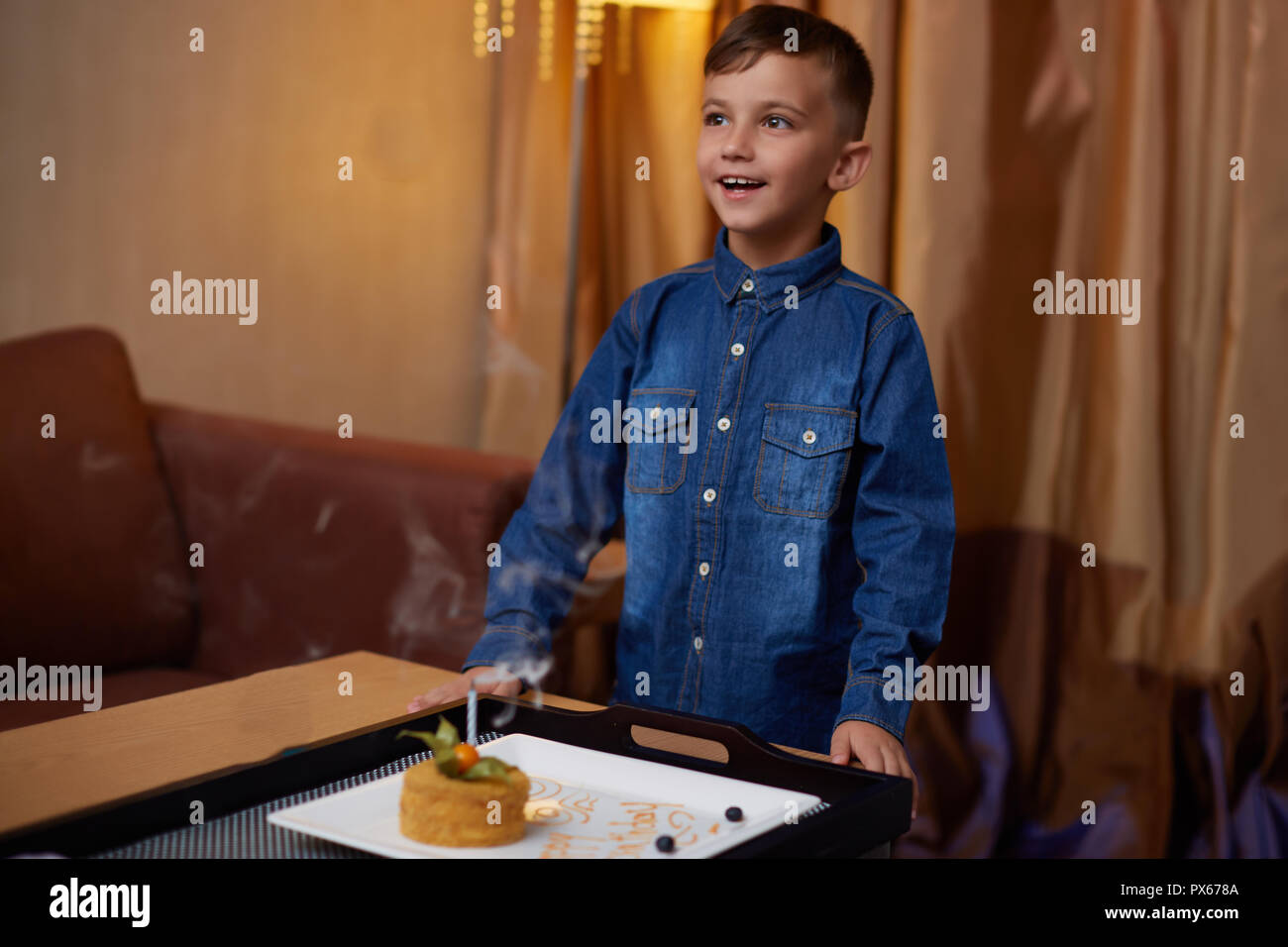 Petit enfant souriant boy blowing anniversaire gâteau sucré candle fire Banque D'Images