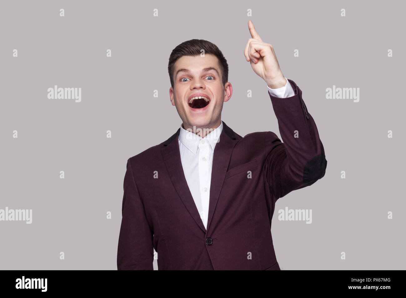 J'ai une bonne idée. Portrait of happy satisfait beau jeune homme en costume violet et chemise blanche, debout, looking at camera avec surprise dans la face. Banque D'Images