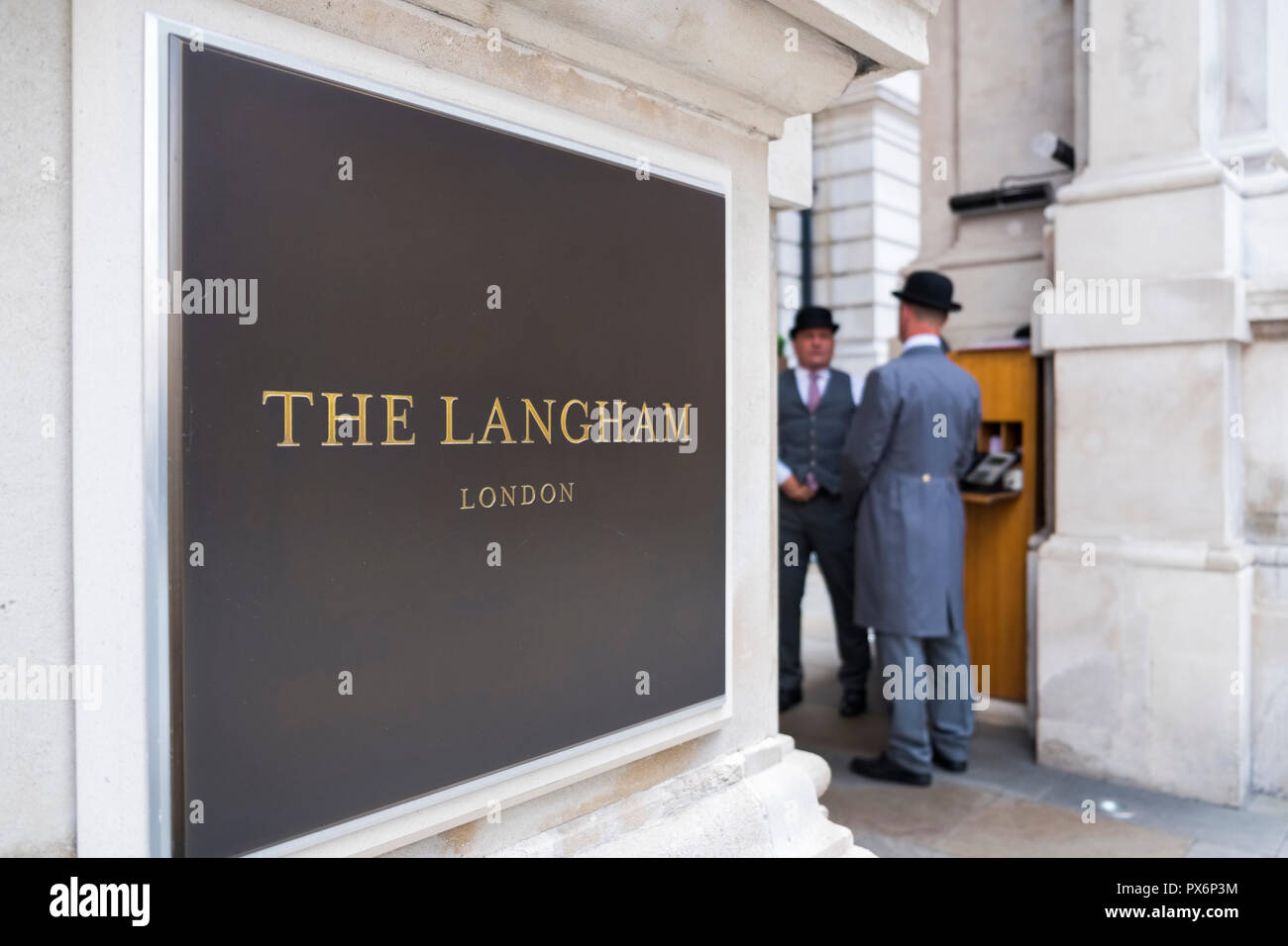 Signe de la plaque signalétique de l'hôtel Langham dans W1, Londres, Angleterre, Royaume-Uni, avec deux porteurs à l'extérieur portant le traditionnel chapeau melon Banque D'Images