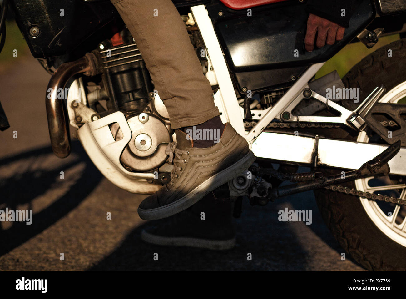 Fermer la vue des jambes dans des chaussures sur une moto Banque D'Images