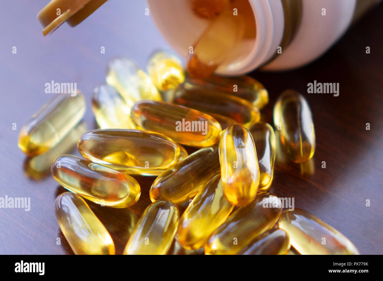 Des capsules d'huile de poisson à l'oméga 3 et de vitamine D dans une bouteille en verre sur la texture en bois, alimentation saine notion,close up shot. Banque D'Images