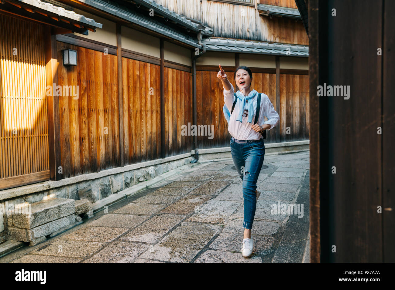 Toute la longueur de female traveler excité et pointant vers temple loin dans le ciel. Jeune femme séduisante en vacances 2 étoiles à pied dans le chemin en Ky Banque D'Images