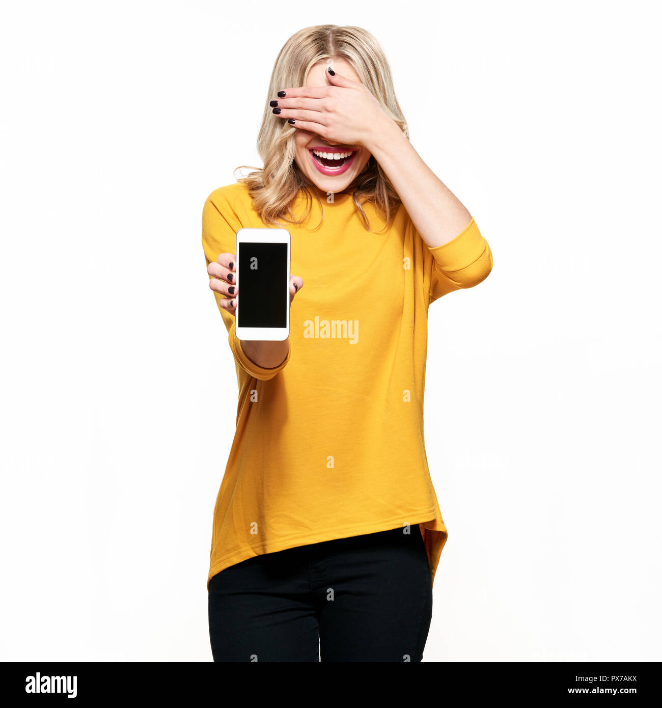Gorgeous laughing woman showing blank écran téléphone sur fond blanc, couvrant ses yeux avec la main. Très excité, encourageant l'émotion. Banque D'Images