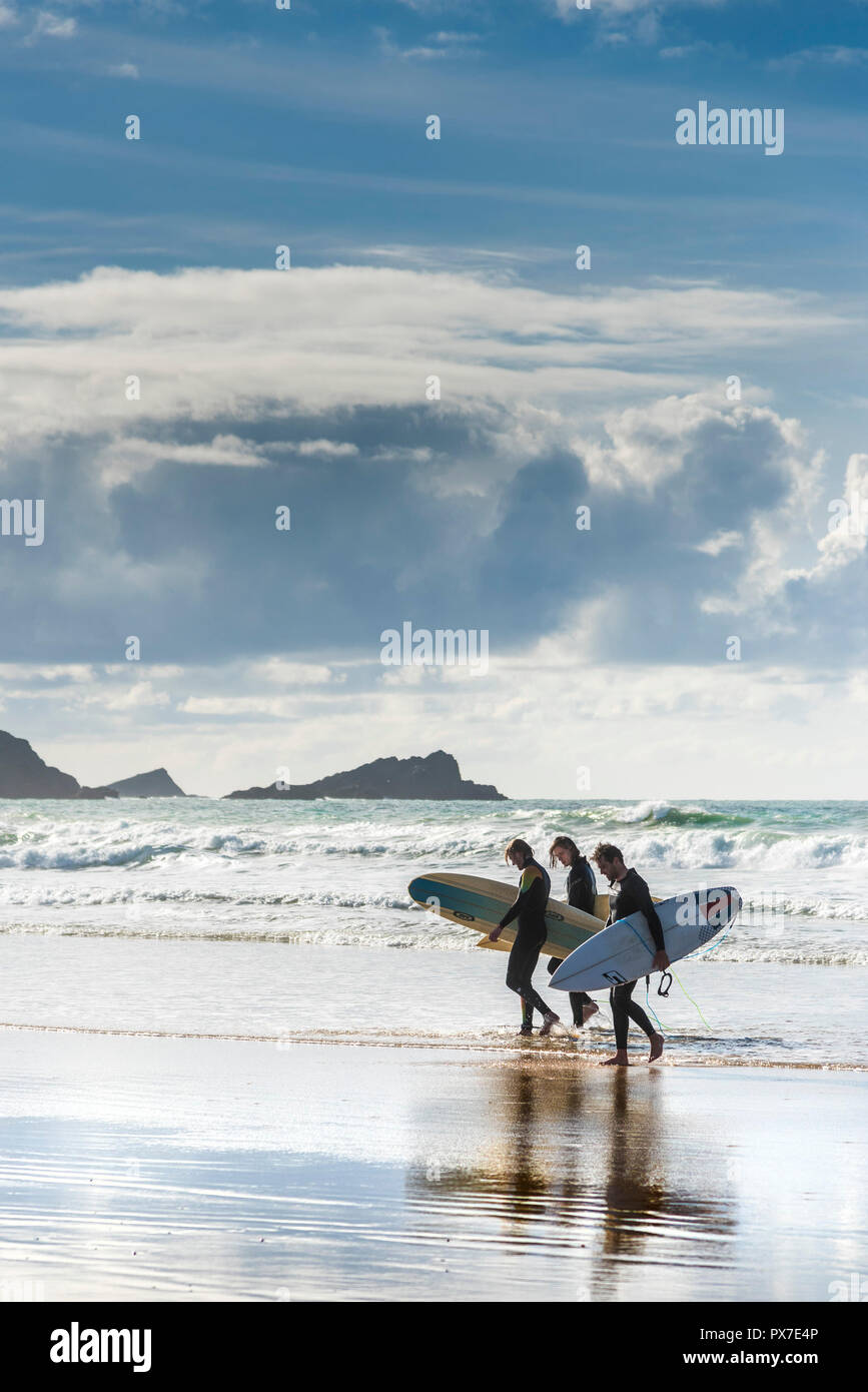 Leurs Surfers carrying surfboards et sortant de la mer à de Fistral Newquay en Cornouailles. Banque D'Images