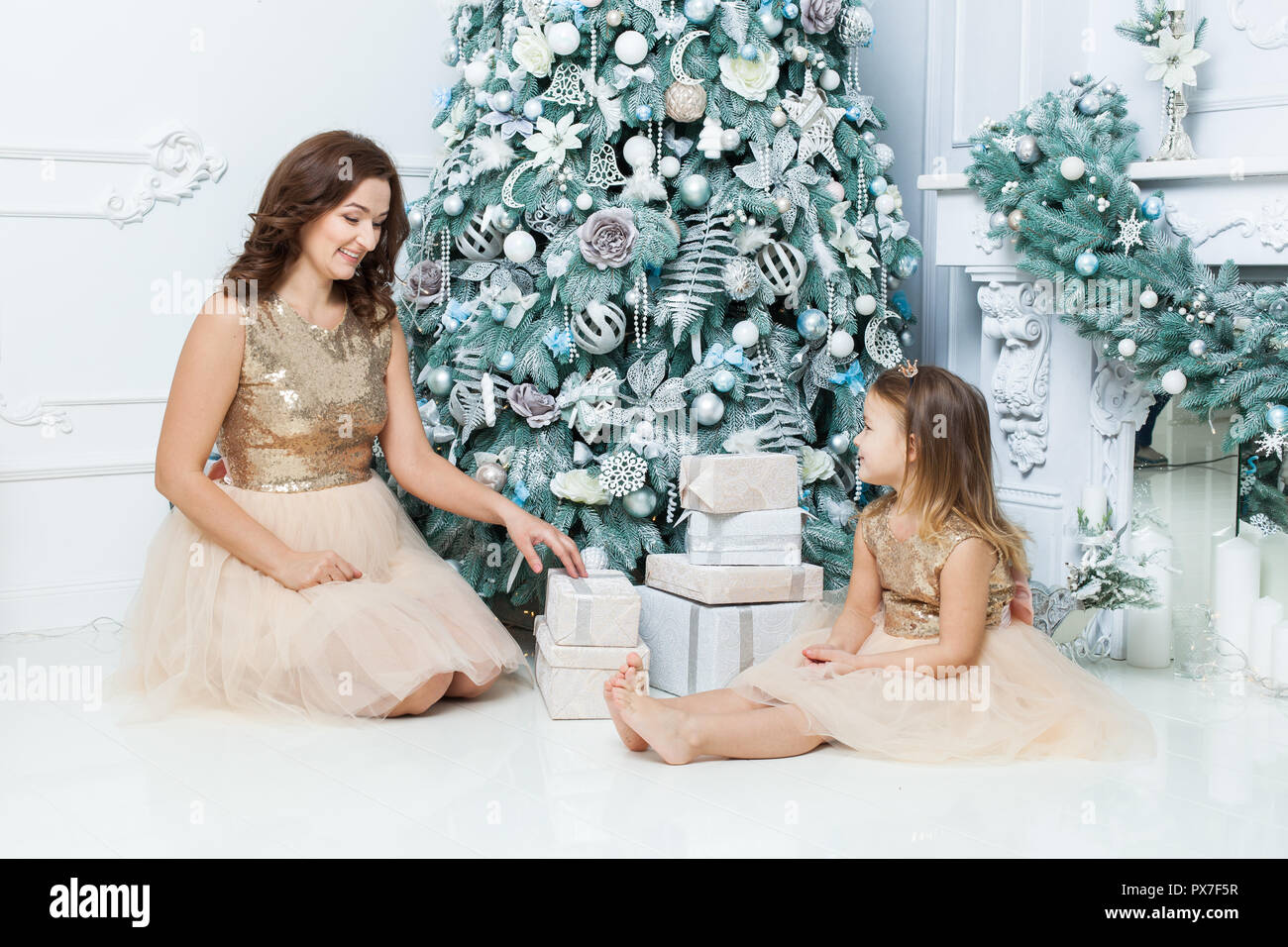 Jeune mère et fille sous l'arbre de Noël près de la boîtes à cadeaux. Banque D'Images