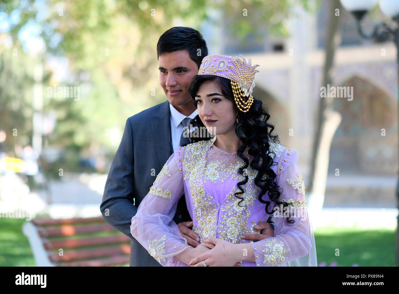 Un marié ouzbek pose avec une mariée portant une casquette traditionnelle en tubeteika lors d'une séance de photographie pré mariage dans la vieille ville de Boukhara en Ouzbékistan Banque D'Images