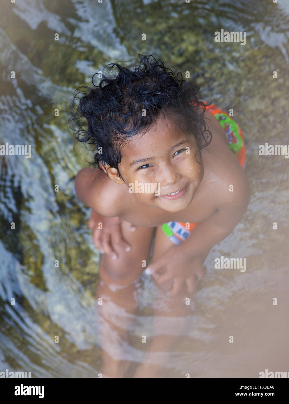 Une jeune fille assise dans une rivière de l'appareil photo , Thaïlande Banque D'Images