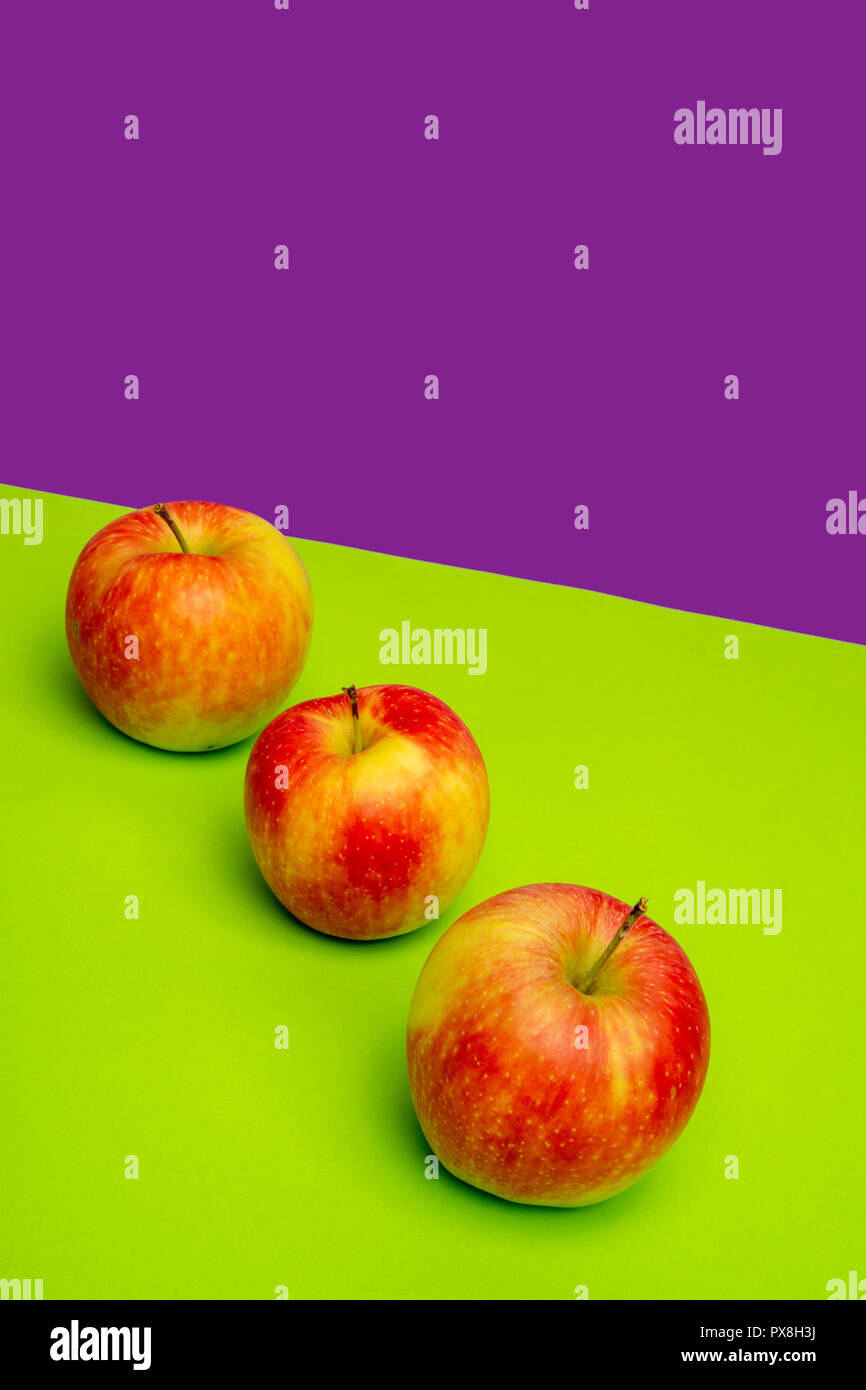 Grenaille verticale de trois pommes placées sur une surface colorée Banque D'Images