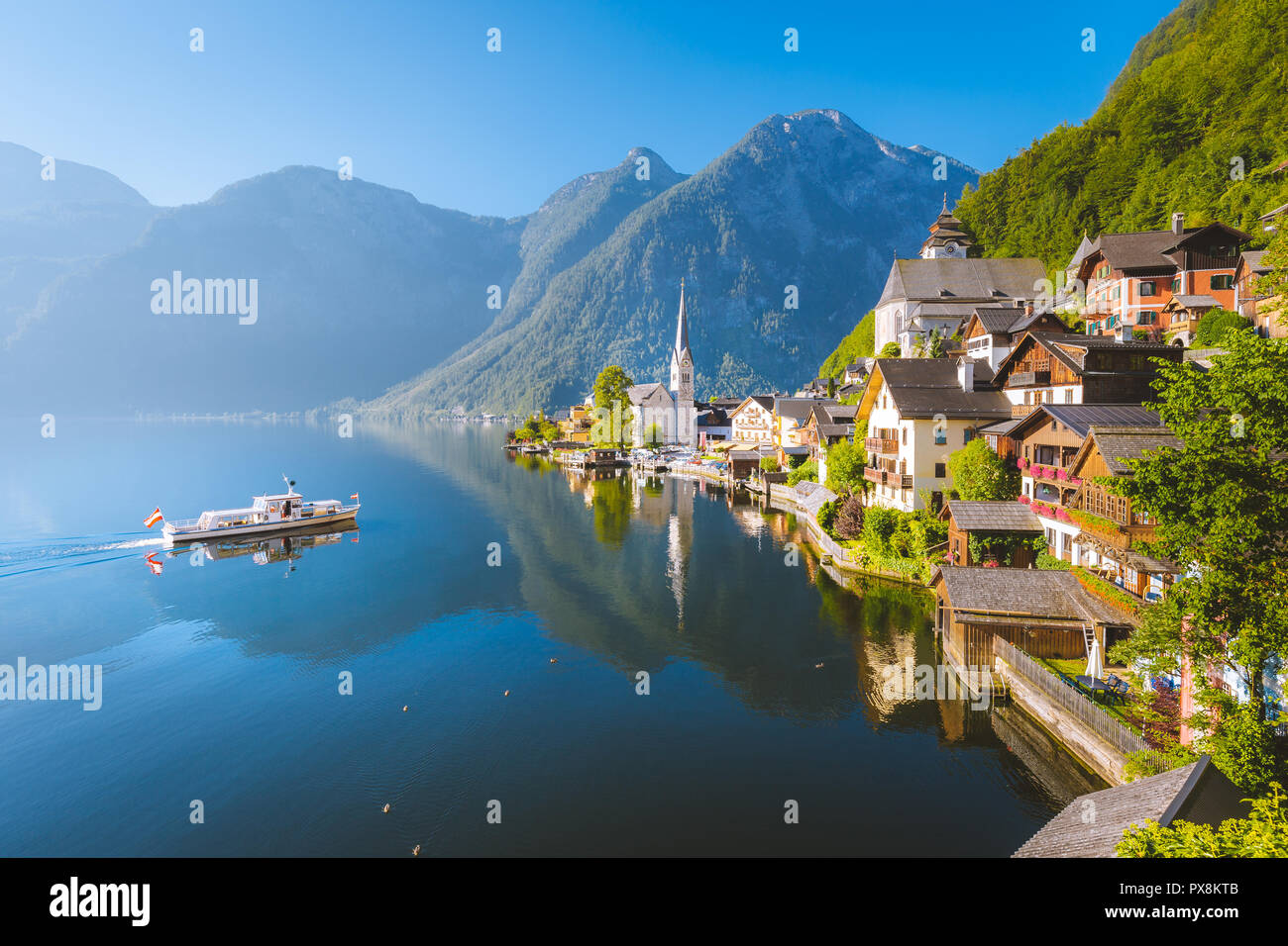 Vue de carte postale classique de la célèbre ville au bord du lac de Hallstatt avec navire traditionnel dans la belle lumière du matin au lever du soleil en été, Salzkammergut, Autriche Banque D'Images