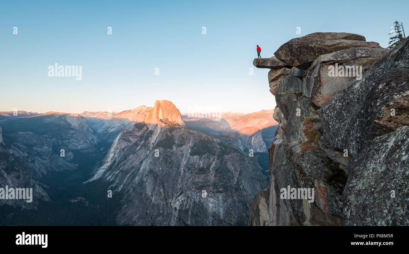 L'intrépide randonneur est debout sur un rocher en surplomb en profitant de la vue vers célèbre Demi Dôme à Glacier Point oublier dans beau crépuscule du soir Banque D'Images