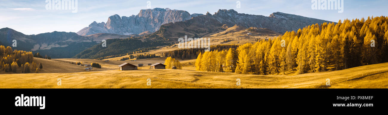 Belle vue sur la montagne chalets traditionnels en bois sur Scenic Alpe di Siusi célèbre Langkofel avec des pics de montagne dans l'arrière-plan dans la matinée d'or Banque D'Images