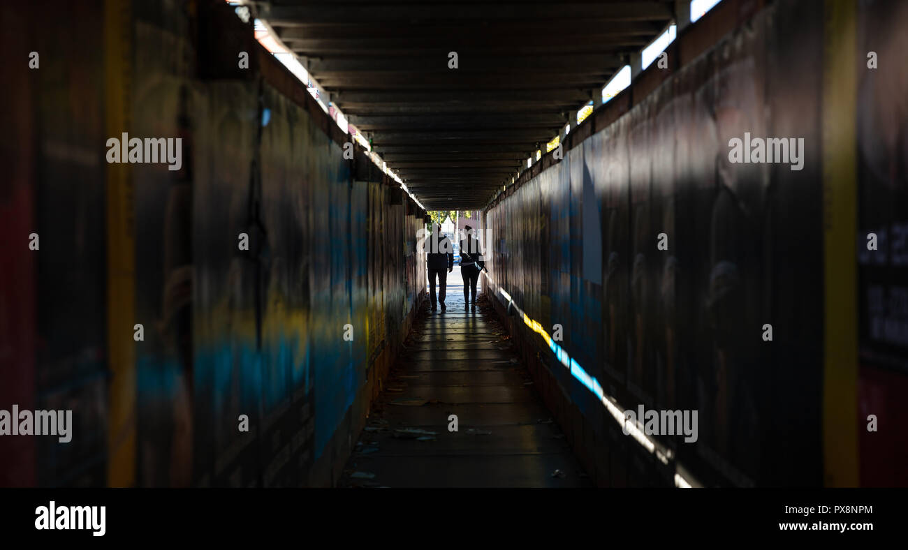 La lumière au bout du tunnel. Jeune couple en train de marcher dans un sombre couloir de protection pour les piétons Banque D'Images La lumière au bout du tunnel. Jeune couple en train de marcher dans un sombre couloir de protection pour les piétons Banque D'Images