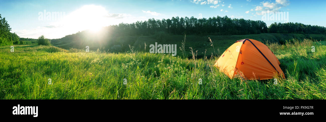 Orange tente sur un pré vert. Panorama. Paysage d'été. Le concept de la vie privée, la liberté de déplacement et. Banque D'Images