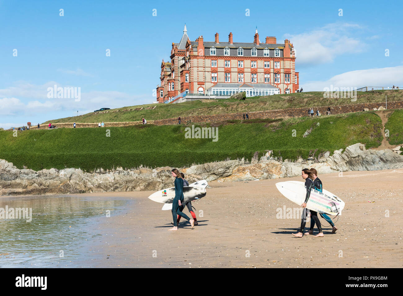 Un groupe de surfers portant leurs planches de pied jusqu'à la mer à la plage de Fistral à Newquay en Cornouailles. Banque D'Images