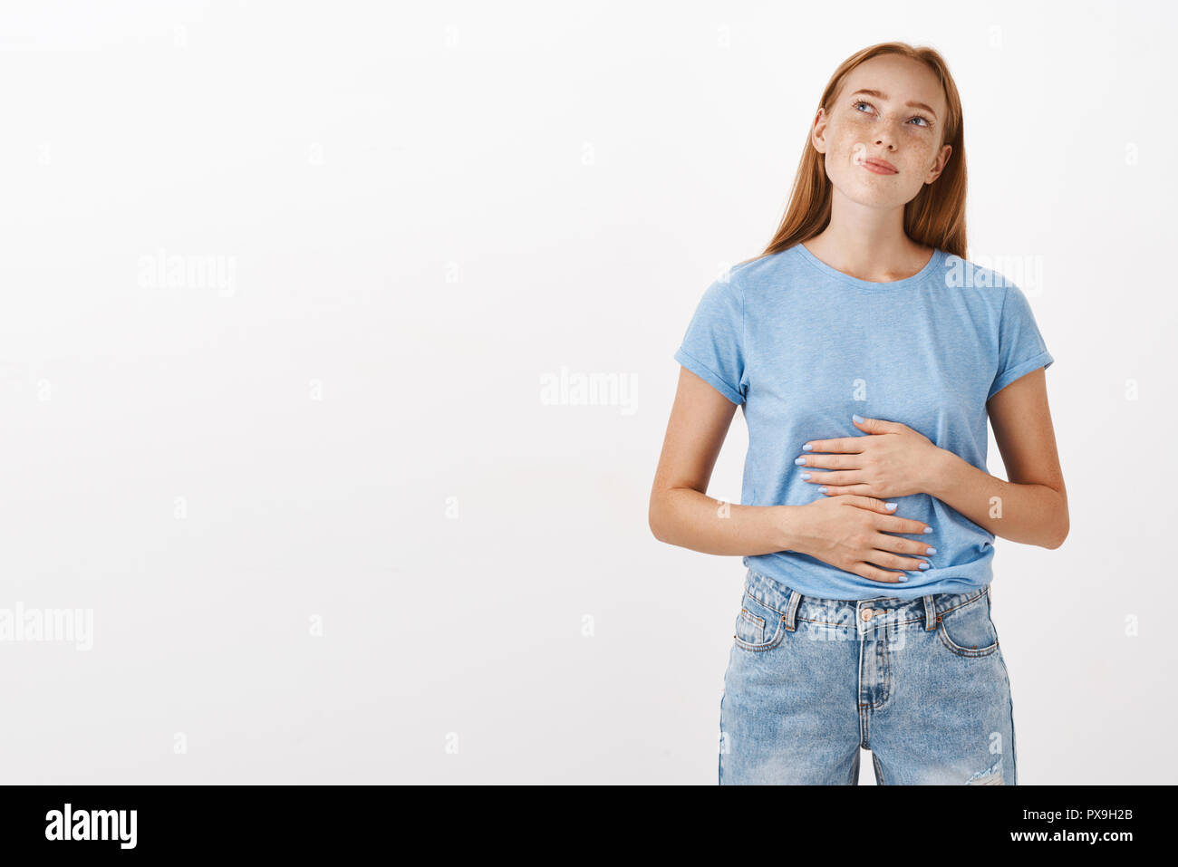 Se souvenir femme savoureuse elle mangeait à nouveau restaurant ou le ventre à ventre frottant le coin en haut à gauche nostalgique et heureux aimer manger de délicieux repas debout dans tee-shirt bleu sur fond gris Banque D'Images