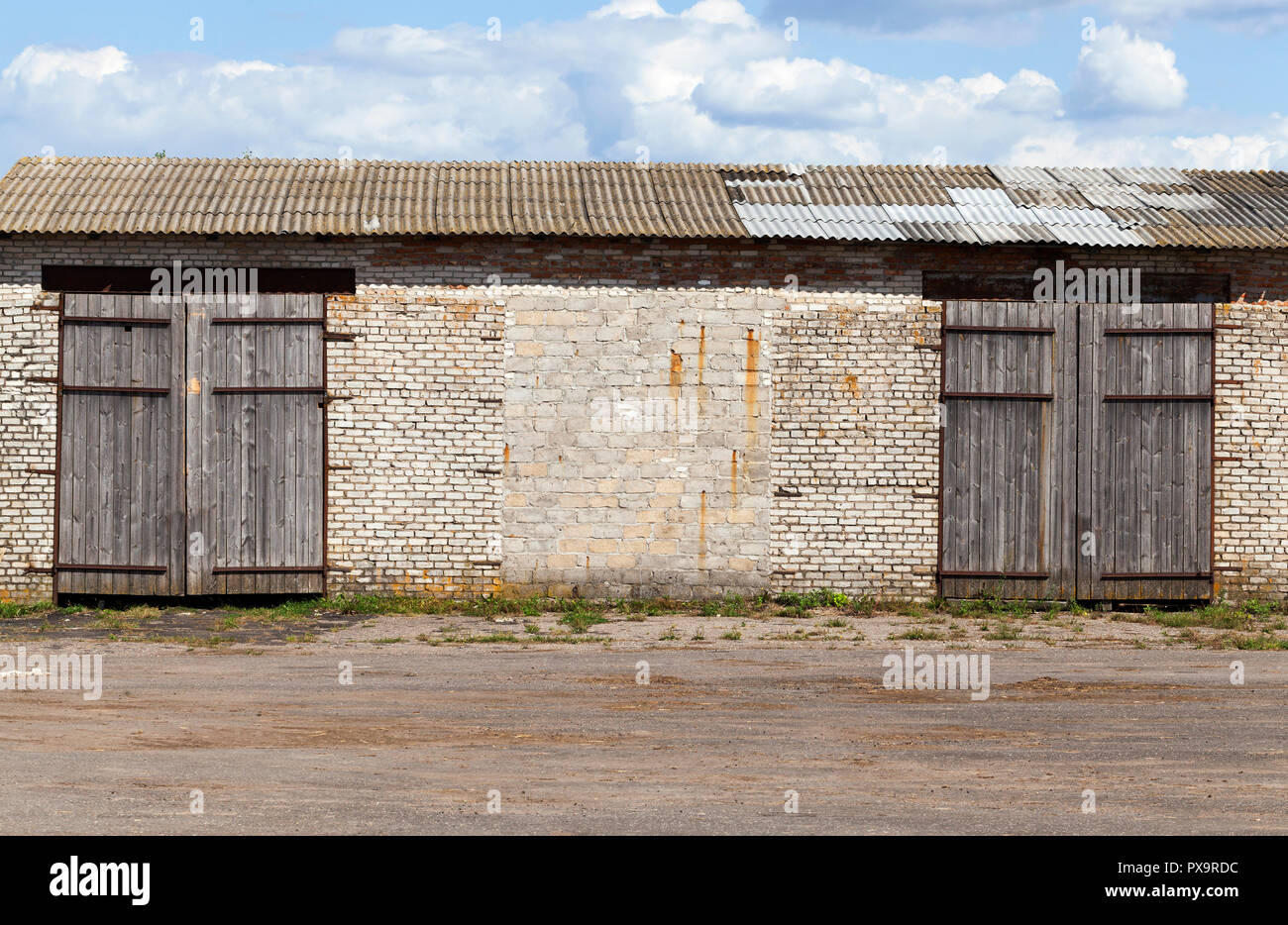 Ancien entrepôt de brique avec de grandes portes fermées, ciel bleu Banque D'Images