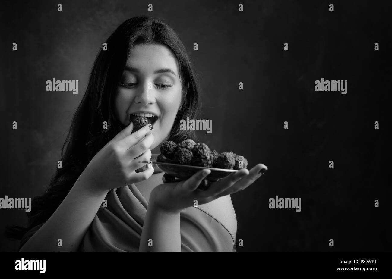 Portrait d'une jeune fille belle avec du chocolat et des bonbons. Noir et blanc. Banque D'Images