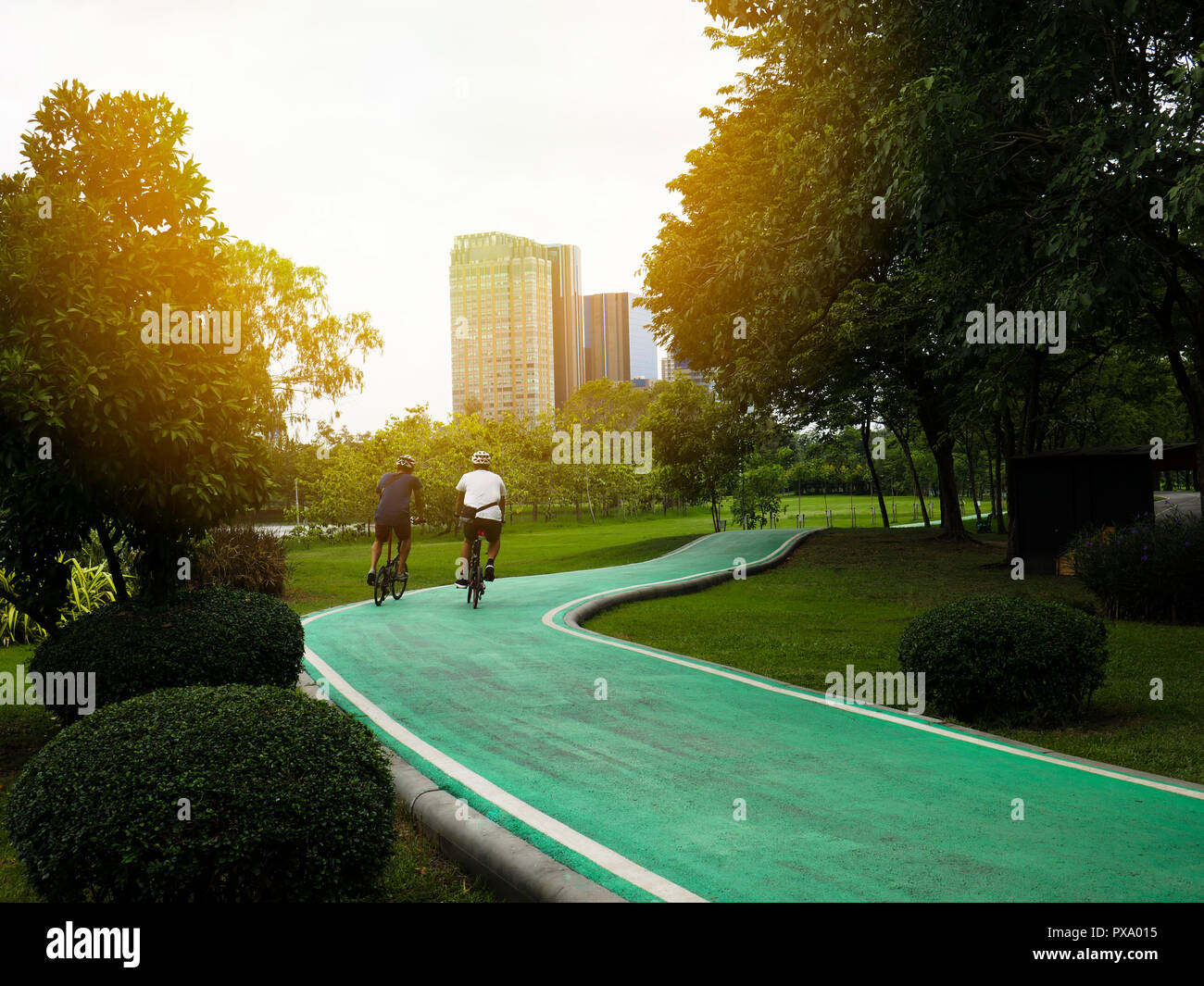 Deux hommes sont à vélo sur une piste cyclable dans un parc public. Banque D'Images