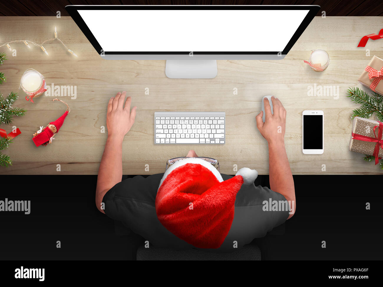 Table de travail pendant la période de Noël. L'homme travaille sur un ordinateur. Bougies de Noël, arbre et cadeaux à côté. Vue d'en haut. Banque D'Images