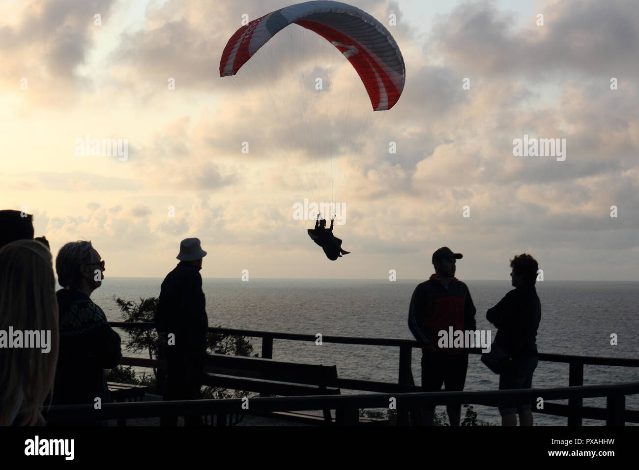 Un groupe de personnes debout sur la terrasse panoramique et regarder un para-planeur voler au-dessus de la mer. Banque D'Images
