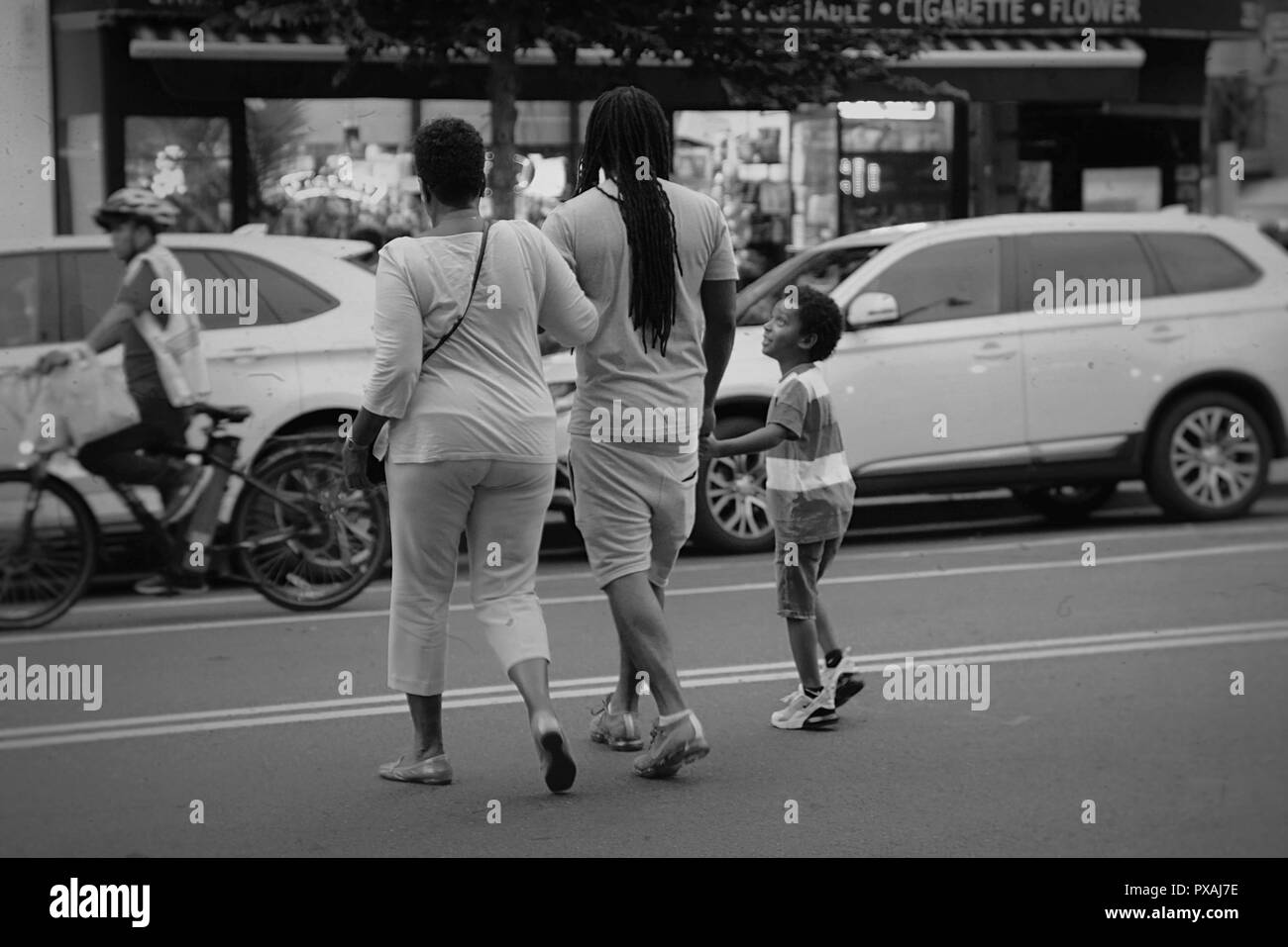Brooklyn, NY ; Août 2018 : une famille marche main dans la main alors qu'ils traversent la rue en noir et blanc Banque D'Images
