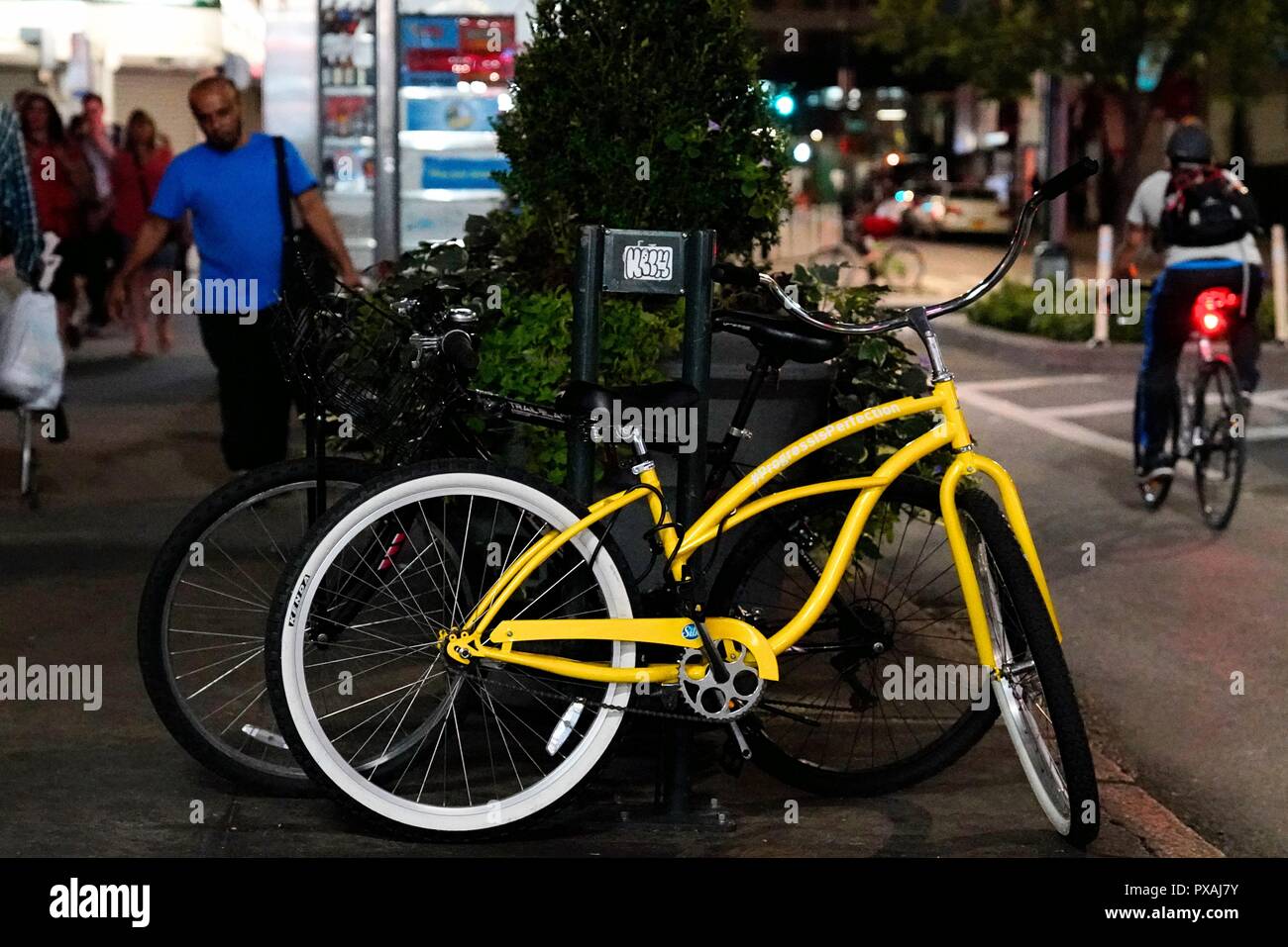 New York, NY ; Août 2018 : un vélo jaune lumineux, enchaîné sur le trottoir Banque D'Images