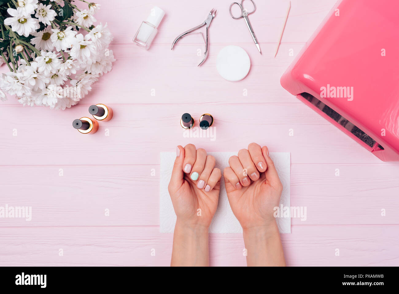 Flatlay femme de mains avec shellac couvrant pendant la procédure. manucure Vue supérieure du processus de composition de fête avec des clous peinture vernis à ongles gel près de Banque D'Images