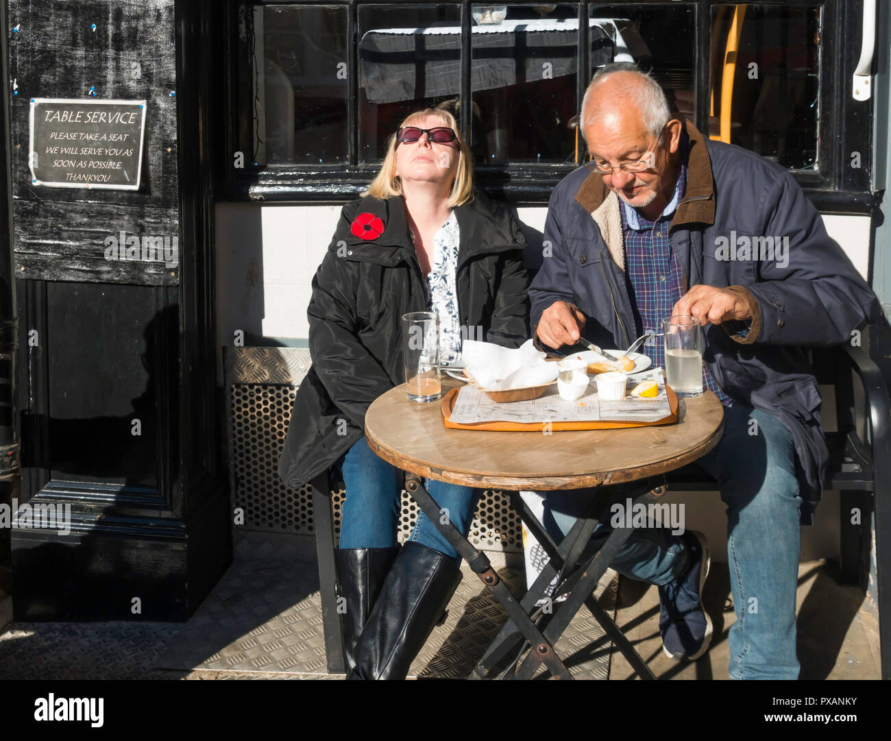 Homme et une femme de manger dehors à l'extérieur d'un café à Whitby, North Yorkshire, woman l'automne Sunshine Banque D'Images