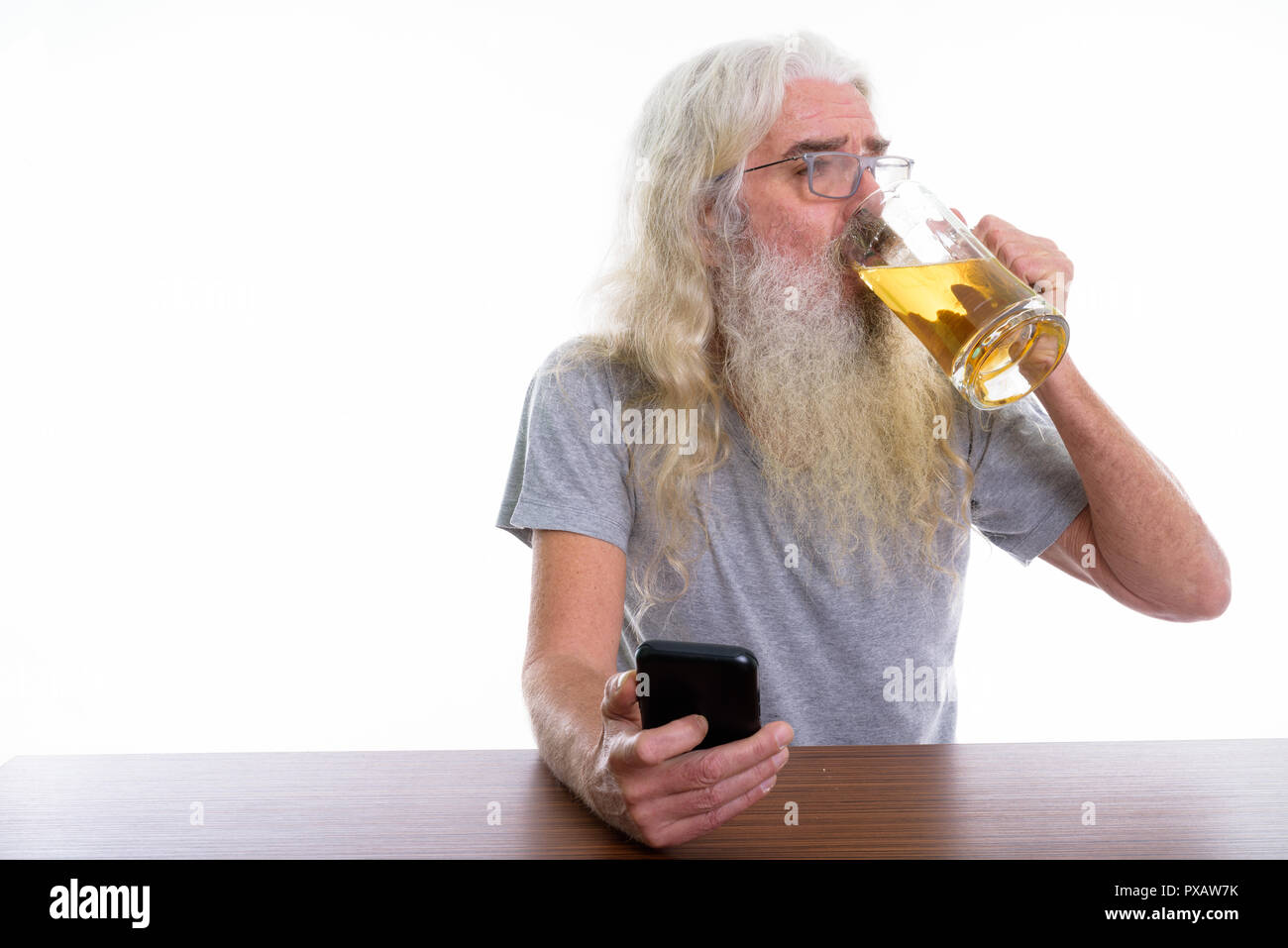 Studio shot of senior homme barbu holding mobile phone et verre Banque D'Images
