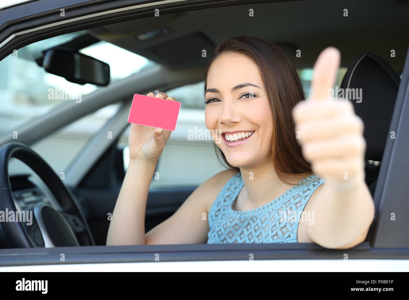 Heureux conducteur montrant une carte vierge ou licence avec Thumbs up à l'intérieur d'une voiture Banque D'Images