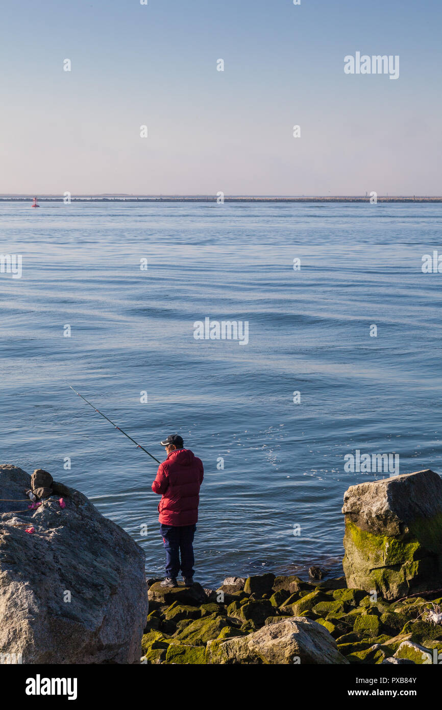 Homme dans un manteau rouge pêche le bras sud du fleuve Fraser Banque D'Images