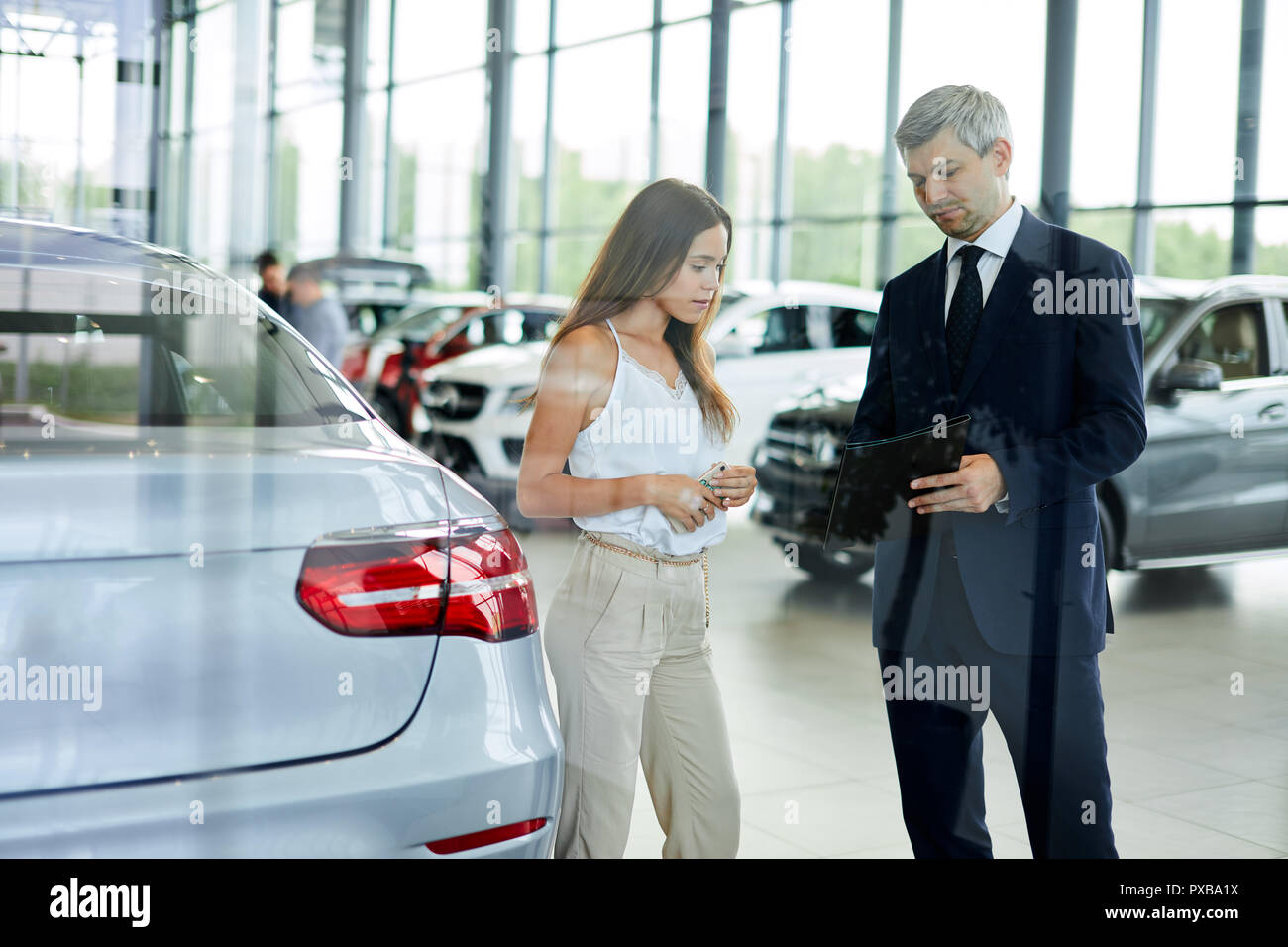 Jeune femme mature demande client sales manager pour aider à l'agence de voiture. Banque D'Images