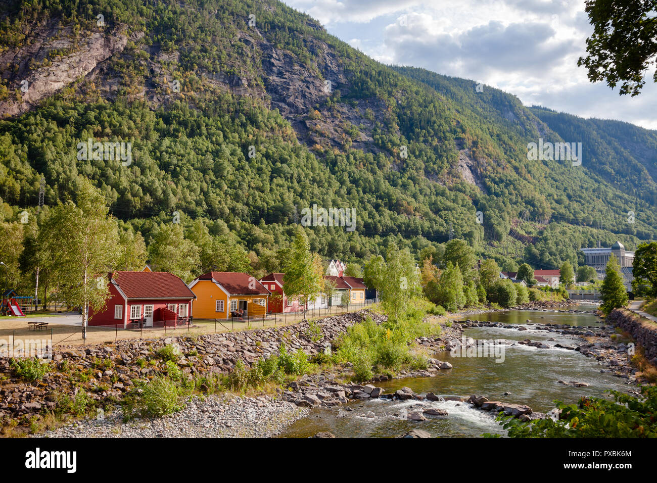 RJUKAN, NORVÈGE - 14 juillet 2018 Résidentiel : maisons en bois le long de la rivière Mana avec l'Saheim Station d'énergie hydroélectrique à l'arrière-plan, Rjukan-Notodden U Banque D'Images