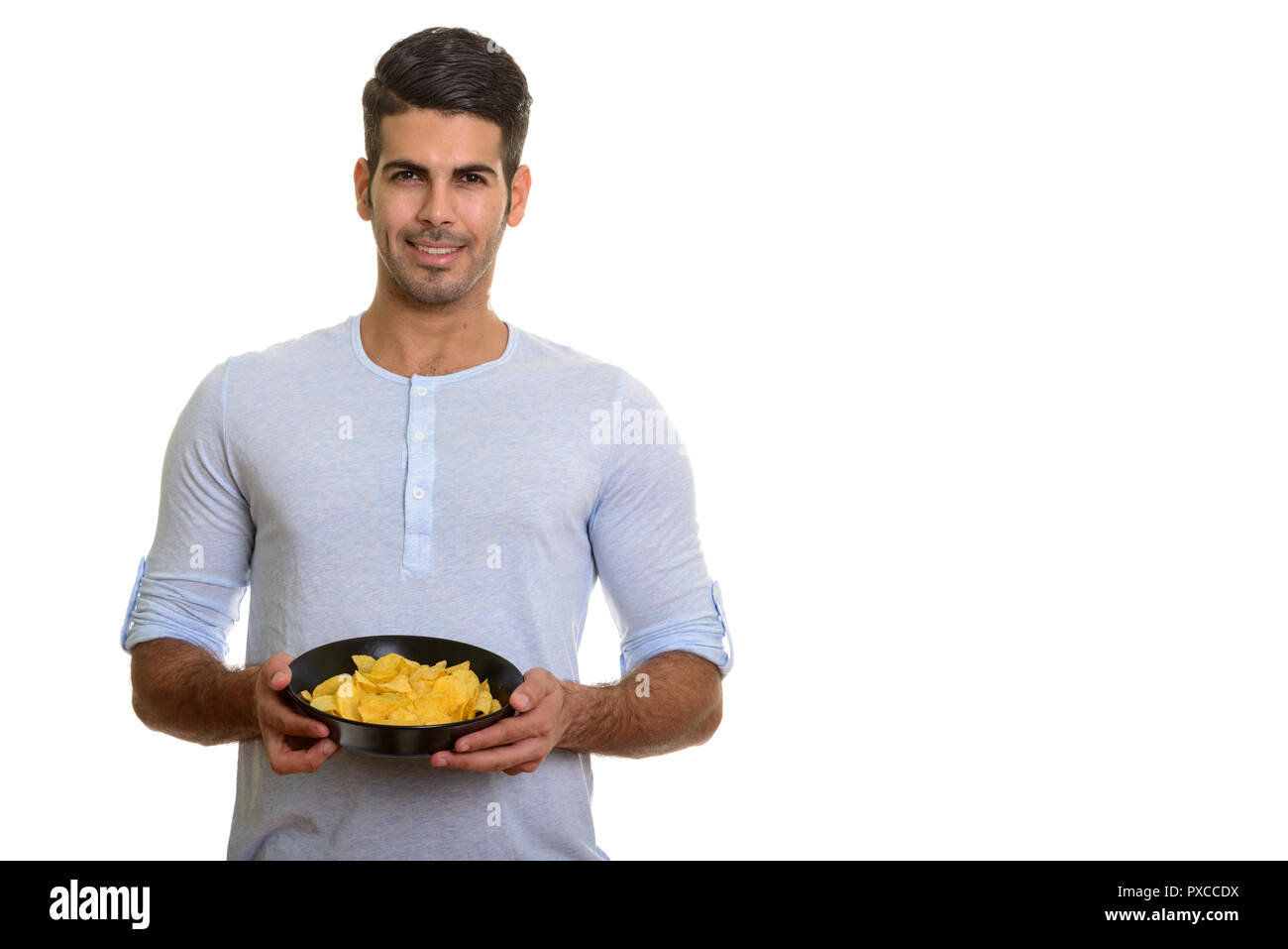 Les jeunes professionnels Persian man smiling and holding bowl of potato chips Banque D'Images