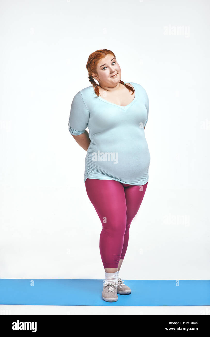 Image drôle de comique, aux cheveux rouges, chubby woman on white background. Femme est timide Banque D'Images