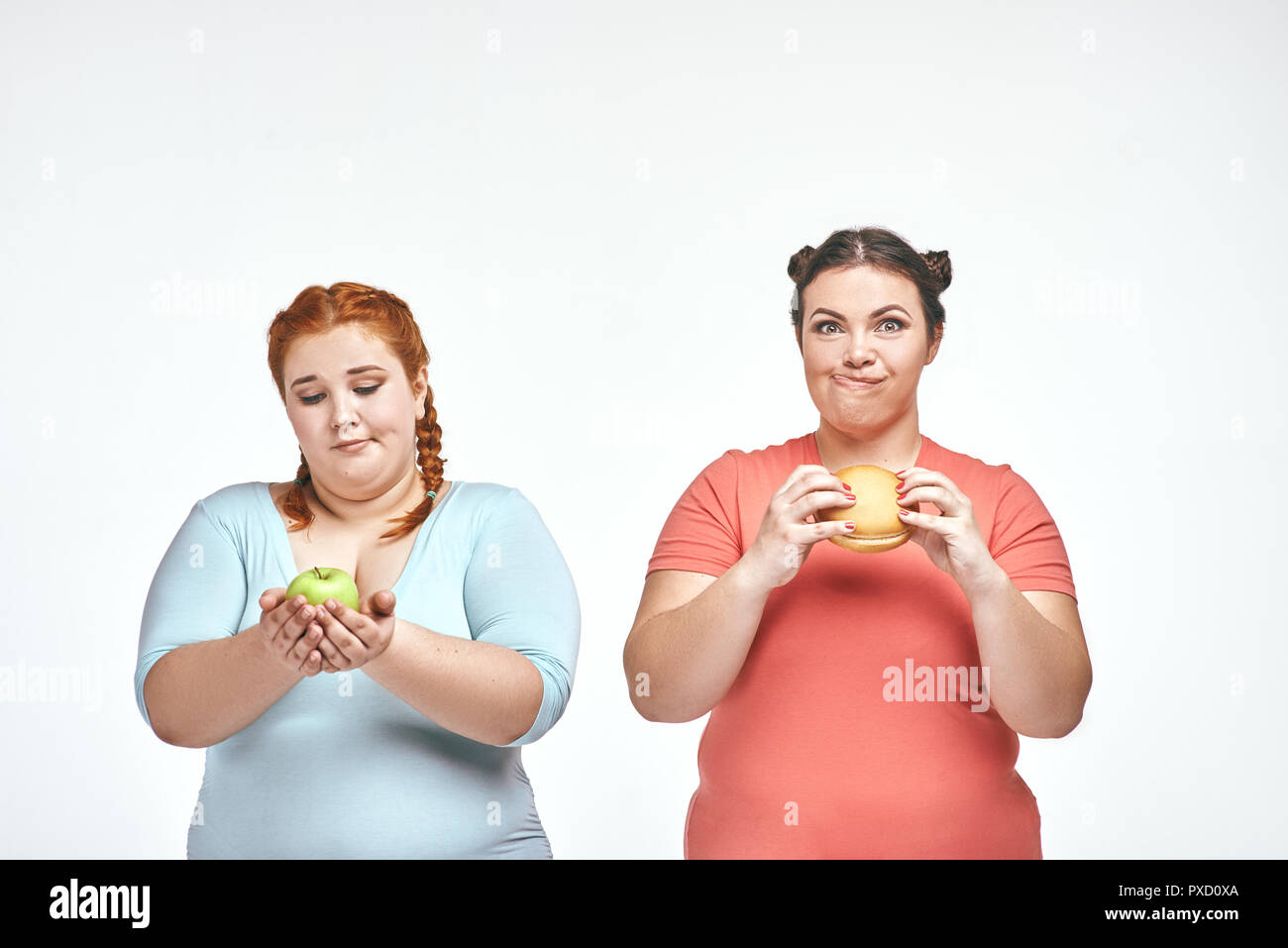 Les femmes potelées : une femme tient un sandwich,un autre holding an apple Banque D'Images