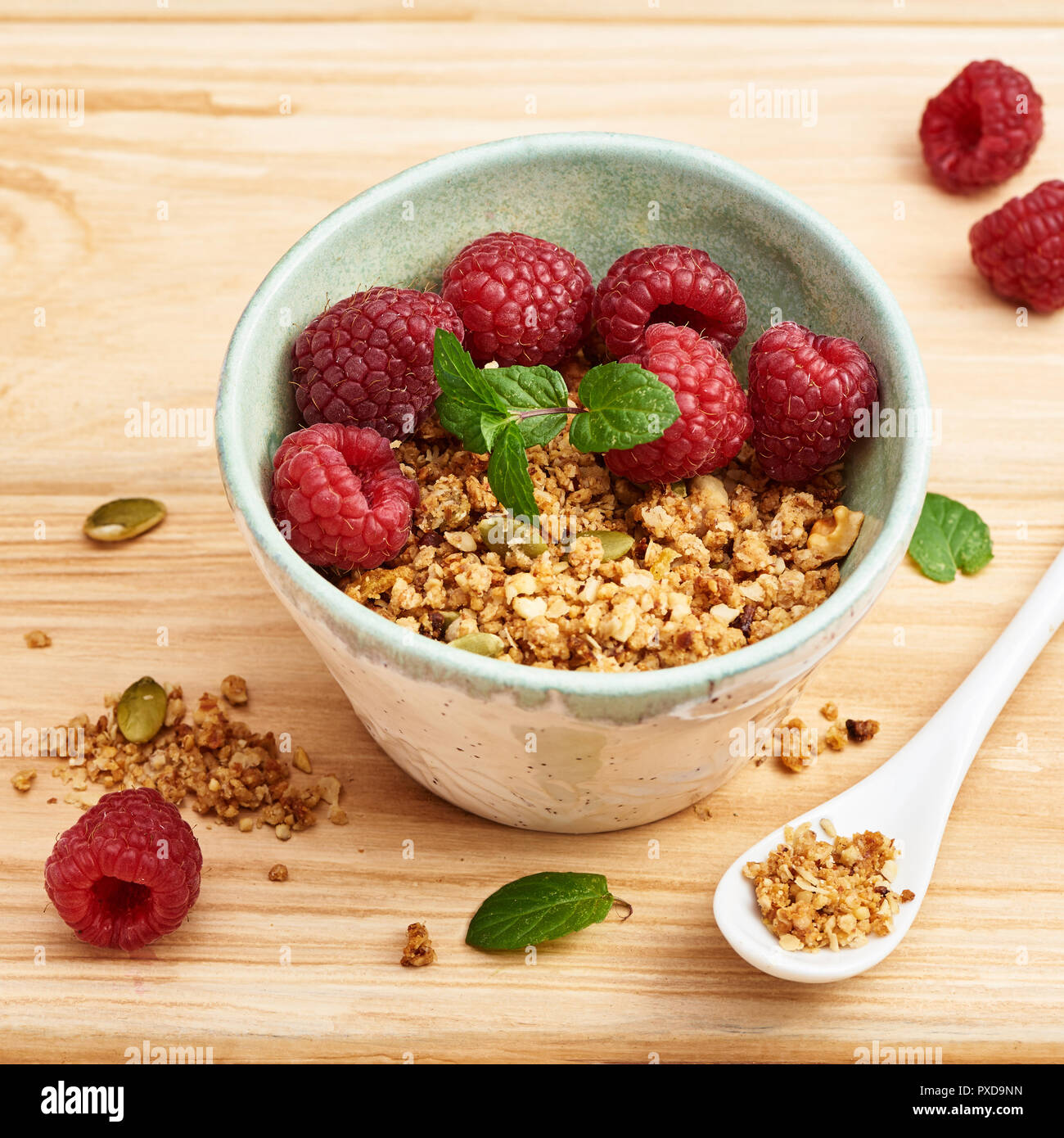 Granola fait maison dans un bol avec les framboises sur la table en bois. Banque D'Images