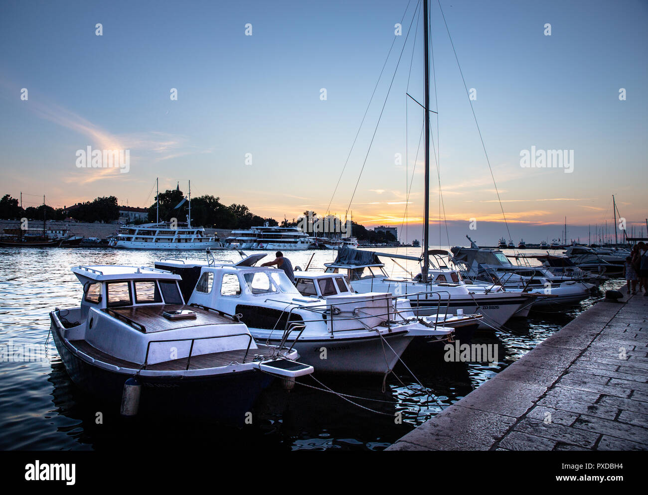 Les petits bateaux et yachts amarrés dans le port de Zadar à vers la vieille ville au coucher du soleil Banque D'Images