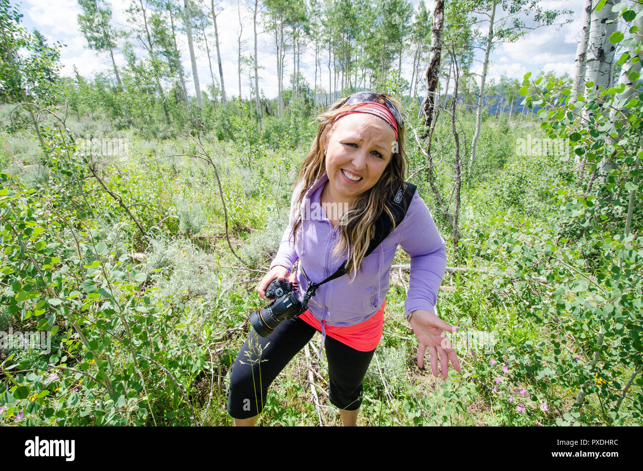 Appréhensif femme donne pas sûr, prudent comme elle émerge de la forêt essayant de randonnée pédestre sans les vêtements et équipement. Caméra comptable Banque D'Images