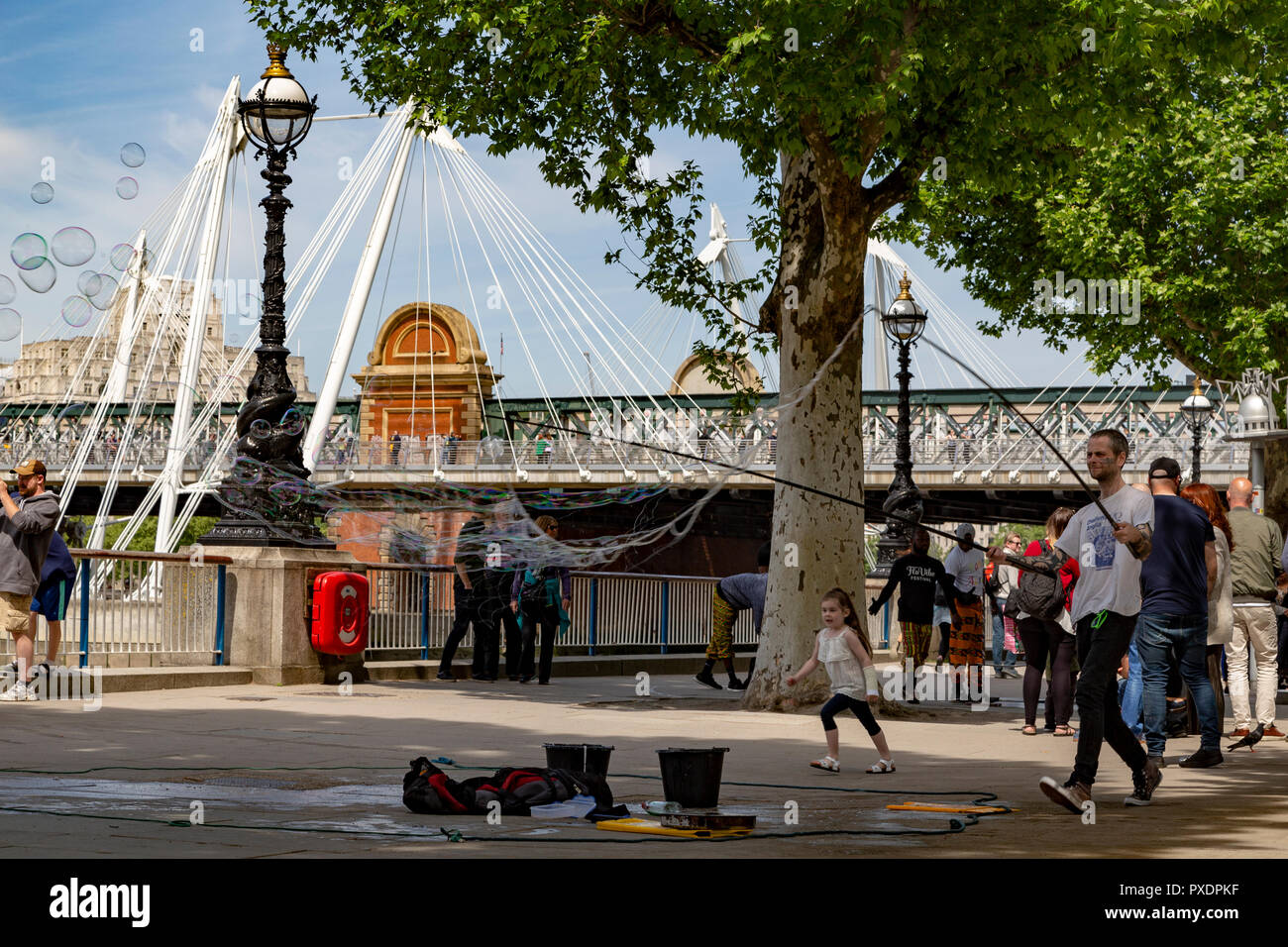 Jeune fille chassant avec ballons savon Hungerford Bridge en arrière-plan, London, UK Banque D'Images
